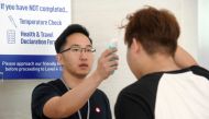 This photograph taken on February 22, 2020 shows a volunteer (L) taking a temperature of a church member attending a small group service as a protective measure to prevent the spread of the COVID-19 coronavirus in Singapore. AFP / Roslan RAHMAN