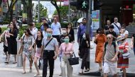  People, some wearing a protective facemask amid fears about the spread of the COVID-19 novel coronavirus, crosses the road in Singapore on February 26, 2020. (Photo by Roslan RAHMAN / AFP) 