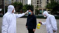This photo taken on February 28, 2020, shows a factory employee being disinfected and his temperature taken by security guards in protective gear at the entrance of the Azure Eyeglasses Company in Wenzhou. FOCUS BY DAN MARTIN / AFP / NOEL CELIS /