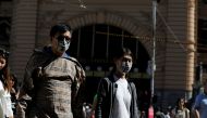  FILE PHOTO: People wearing face masks walk by Flinders Street Station after cases of the coronavirus were confirmed in Melbourne, Victoria, Australia, January 29, 2020. REUTERS/Andrew Kelly/File Photo 