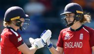 England's Heather Knight (L) Natalie Sciver bump gloves during the Twenty20 women's World Cup cricket match between England and Thailand in Canberra on February 26, 2020. - / AFP / Peter PARKS / 