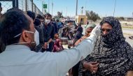 A health personnel checks the body temperature of a pilgrim returning from Iran via the Pakistan-Iran border town of Taftan on February 29, 2020. Health officials in Pakistan are screening hundreds of people who had recently arrived from Iran, a major new