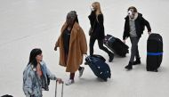 Travellers wearing protective face masks pull their suitcases while walking across the concourse at London Victoria train station in central London on March 3, 2020. AFP / Justin Tallis   