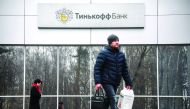People walk past the logo of the Tinkoff Bank headquarters in Moscow on March 6, 2020.  AFP / Alexander Nemenov
