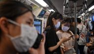 People wearing face masks ride the BTS Skytrain station in Bangkok on March 7, 2020.  AFP / Lillian SUWANRUMPHA
