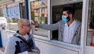 A Cypriot medic checks the temperature of a man crossing the Ledra Palace checkpoint in Nicosia on March 4, 2020. AFP / Iakovos Hatzistavrou