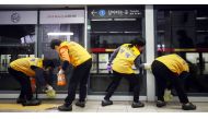Workers disinfect a screen door to help prevent the spread of the COVID-19 coronavirus, at a subway station in Seoul on March 11, 2020./ AFP / YONHAP / 