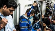 A commuter (C) wearing a facemask as a preventive measure against the spread of the COVID-19 coronavirus uses his phone while travelling on the Violet Line of the Delhi Metro, in New Delhi on March 12, 2020. / AFP / XAVIER GALIANA