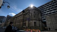 A pedestrian walks in front of the Bank of Japan headquarters in Tokyo on March 16, 2020. The Bank of Japan on March 16 unveiled a series of emergency monetary policy measures to shore up the world's third-largest economy, as the coronavirus pandemic thre