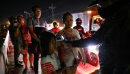A girl holds on to her mother as a police officer checks her body temperature at a checkpoint placed amidst the lockdown of the country's capital to contain the spread of coronavirus, in the outskirts of Quezon City, Metro Manila, Philippines, March 15, 2
