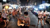  This photo taken on March 14, 2020 shows a man busking in a face mask at an unusually-empty night market in Chiang Mai, as the number of visitors to the region has plunged due to the outbreak of the COVID-19 coronavirus. / AFP / Lillian SUWANRUMPHA