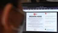 A man reads an announcement by CNN Philippines of their temporary closure from their facebook page, due to a positive COVID-19 infection at their building in Manila on March 18, 2020. / AFP / Ted ALJIBE