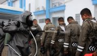 Officials from a police unit spray each other before performing disinfecting measures at the tourist area of Gili Trawangan on Lombok island on March 18, 2020, amid concerns of the COVID-19 coronavirus outbreak. / AFP / PIKONG