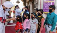 Health workers (L and C) wearing facemasks check the body temperature of devotees amid concerns over the spread of the COVID-19 novel coronavirus, at the entrance of the Durgiana Temple in Amritsar on March 18, 2020. AFP / Narinder Nanu 
