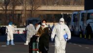 Staff in protective suits accompany passengers outside a centralized facility for screening and registration near the Beijing Capital International Airport in Beijing as the country is hit by an outbreak of the novel coronavirus, China, March 17, 2020. RE
