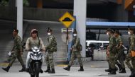 A motorcyclist rides past soldiers inside a police station during the control of movement in Kuala Lumpur on March 22, 2020, amid fears over the spread of the COVID-19 novel coronavirus. / AFP / Mohd RASFAN
