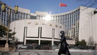 FILE PHOTO: A woman wearing a mask walks past the headquarters of the People's Bank of China, the central bank, in Beijing, China, as the country is hit by an outbreak of the new coronavirus, February 3, 2020. REUTERS/Jason Lee/File Photo