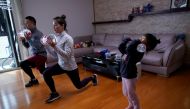 Dino Lin, Stella Zhang and Wowo Lin, 5, exercise using filled water bottles as weights as they watch a fitness class online at their house, during the novel coronavirus disease (COVID-19) outbreak, in Shanghai, China, February 25, 2020. Reuters/Aly Song 