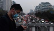 A man walks past wearing a face mask as cars crowd the Second Ring Road in Beijing amid the ongoing COVID-19 coronavirus outbreak on March 24, 2020.   AFP / GREG BAKER
