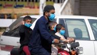 A man and his children wearing facemasks ride on a motorbike along a street during a government-imposed lockdown as a preventive measure against the COVID-19 in Rawalpindi on March 25, 2020. AFP / Farooq Naeem 