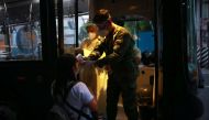 A soldier checks the body temperature of a health worker before entering a free shuttle service following the suspension of mass transportation to contain the spread of coronavirus disease (COVID-19), in Quezon City, Metro Manila, Philippines, March 20, 2