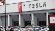 Telsa employees work outside a tesla showroom in Burbank, California, March 24, 2020. / AFP / Robyn Beck