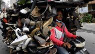 A man rides a motorcart loaded with secondhand shoes for sale along a street in Phnom Penh on March 24, 2020. AFP / Tang Chhin Sothy 