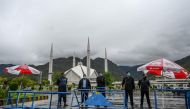 Policemen wearing facemasks stand guard at a checkpoint beside the Grand Faisal Mosque during a government-imposed nationwide lockdown as a preventive measure against the COVID-19 coronavirus, in Islamabad on March 27, 2020. / AFP / Aamir QURESHI
