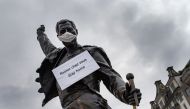 A photograph taken on March 23, 2020 in Montreux shows the statue of Queen's late singer Freddie Mercury wearing a protective facemask and adorned with a placard with a message raising awareness against the spread of the COVID-19 (novel coronavirus), on t