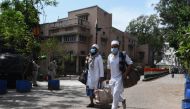 Men wearing a protective facemasks walk to board a special service bus taking them to a quarantine facility amid concerns about the spread of the COVID-19 coronavirus in Nizamuddin area of New Delhi on March 31, 2020. AFP / Sajjad Hussain 