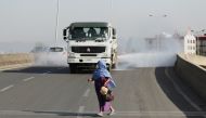 A woman wearing a face mask, runs in front of a truck spraying disinfectant on the street as part of the COVID-19 prevention measures in Addis Ababa, Ethiopia March 29, 2020. Reuters/Tiksa Negeri
 