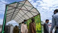 Residents wearing facemasks walk through a disinfecting tunnel at a vegetable and fruit market during a government-imposed nationwide lockdown against the COVID-19 coronavirus, in Islamabad on April 1, 2020. / AFP / Aamir QURESHI
