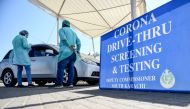 Medical staff members wearing protective gear take information from a resident sitting in a car for a coronavirus test at a drive-through screening and testing facility point during a government-imposed nationwide lockdown as a preventive measure against 