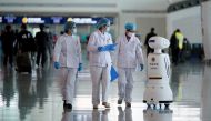 Medical workers walk by a police Robot at the Wuhan Tianhe International Airport after travel restrictions to leave Wuhan, the capital of Hubei province and China's epicentre of the novel coronavirus disease (COVID-19) outbreak, were lifted, April 8, 2020