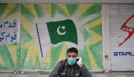 A man wearing a facemask sits in front of a shuttered market during a government-imposed nationwide lockdown as a preventive measure against the COVID-19 coronavirus, in Rawalpindi on April 6, 2020. / AFP / Farooq NAEEM