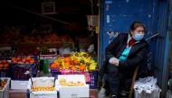 A woman wearing a face mask sits next to a fruit stall at a residential area after the lockdown was lifted in Wuhan, capital of Hubei province and China's epicentre of the novel coronavirus disease (COVID-19) outbreak, April 11, 2020. REUTERS/Aly Song