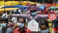 People walk past a Covid-19 awareness scarecrow placed by Chennai municipality at a market during a government-imposed nationwide lockdown as a preventive measure against the COVID-19 coronavirus, in Chennai on April 11, 2020. / AFP / Arun SANKAR