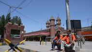 Railway porters sit outside a railway station during a government-imposed nationwide lockdown as a preventive measure against the COVID-19 coronavirus, in Lahore on April 12, 2020. / AFP / ARIF ALI
