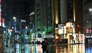 A man wearing a face mask walks with his umbrella in Roppongi district of Tokyo on April 9, 2020. / AFP / Philip FONG