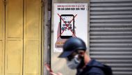 A man uses a smartphone as he walks past a poster warning against spreading 'fake news' on the coronavirus in Hanoi, Vietnam April 14, 2020. Picture taken April 14, 2020. REUTERS/Kham
