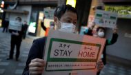Staff members of the Tokyo metropolitan government wearing face masks hold signs as they call for people to stay home after the government announced the state of emergency for the capital and some prefectures following the coronavirus disease (COVID-19) o