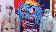 Policemen pose for photos wearing Personal Protective Equipment (PPE)standing next to a poster depicting the COVID-19 coronavirus during an event in Amritsar on April 16, 2020. / AFP / Narinder NANU
