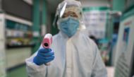 :TOPSHOT - A medical worker prepares to check the temperature of an AFP photojournalist before a COVID-19 coronavirus test in Wuhan in China's central Hubei province on April 16, 2020. / AFP / Hector RETAMAL
