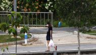 A woman, wearing a face mask as a preventive measure against the spread of the COVID-19 novel coronavirus, carries groceries on her way home in Singapore on April 21, 2020. (AFP / Roslan RAHMAN)