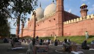 People in need sit maintaining social distancing after collecting free food items outside the Badshahi mosque during a government-imposed nationwide lockdown as a preventive measure against the COVID-19 coronavirus, in Lahore on April 21, 2020. / AFP / AR