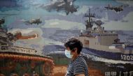 FILE PHOTO: A woman, wearing a protective face mask, walks past a Ministry of National Defense recruitment poster, amid concerns about the coronavirus disease (COVID-19), in Taipei, Taiwan, April 20, 2020. REUTERS/Ann Wang/File Photo
