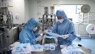 Two workers wearing protective suits check masks at Naton Medical Group, a company which makes medical equipment in Beijing on April 24, 2020. / AFP / WANG ZHAO
