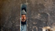 A man is reflected in a mirror as he looks at policemen near the shops during the coronavirus disease (COVID-19) outbreak in Kabul, Afghanistan April 23, 2020.REUTERS/Mohammad Ismail