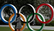 :FILE PHOTO: A woman wearing a protective face mask, following an outbreak of the coronavirus disease (COVID-19), walks past the Olympic rings in front of the Japan Olympics Museum, in Tokyo, Japan March 30, 2020. REUTERS/Issei Kato/File Photo