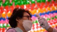 Worshippers wearing face masks have their temperature taken as they attend a prayer ceremony entitled 'overcoming and healing the COVID-19 coronavirus', while marking Buhha's birthday at the Jogye buddhist temple in Seoul on April 30, 2020. / AFP / Ed JON
